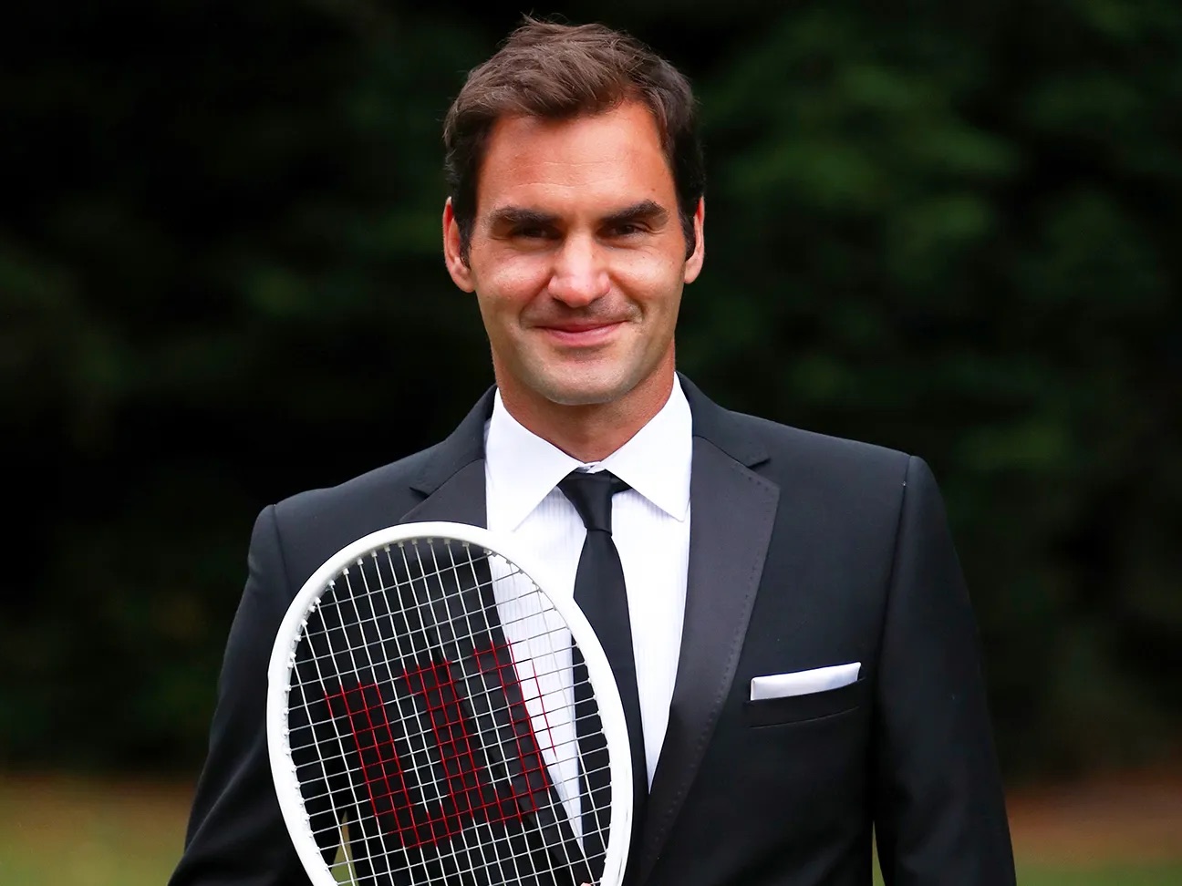 Roger Federer in a tuxedo holding a tennis racket